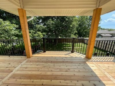 Covered cedar deck with black metal railing overlooking a backyard