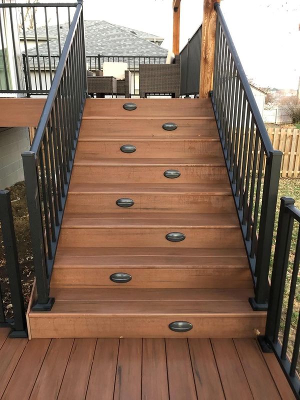 Large wraparound composite deck with covered porch section, ceiling fans, and privacy wall panels, Omaha, NE