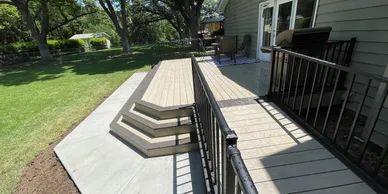 Two-story composite deck with staircase descending to yard and black metal railing, Papillion, NE